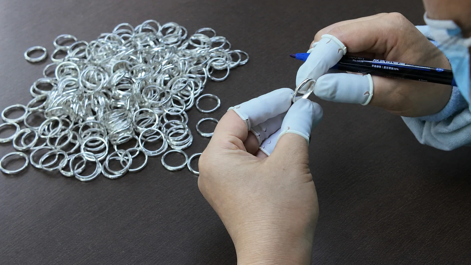 A NOVA inspector reviewing a batch of silver jewelry pieces against the order requirements