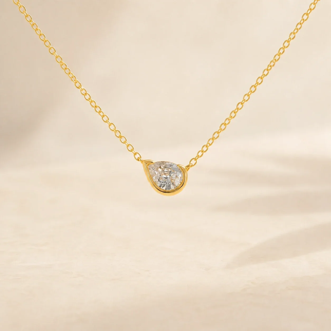 Pure Solitaire pear-stone necklace centred on a warm ivory background