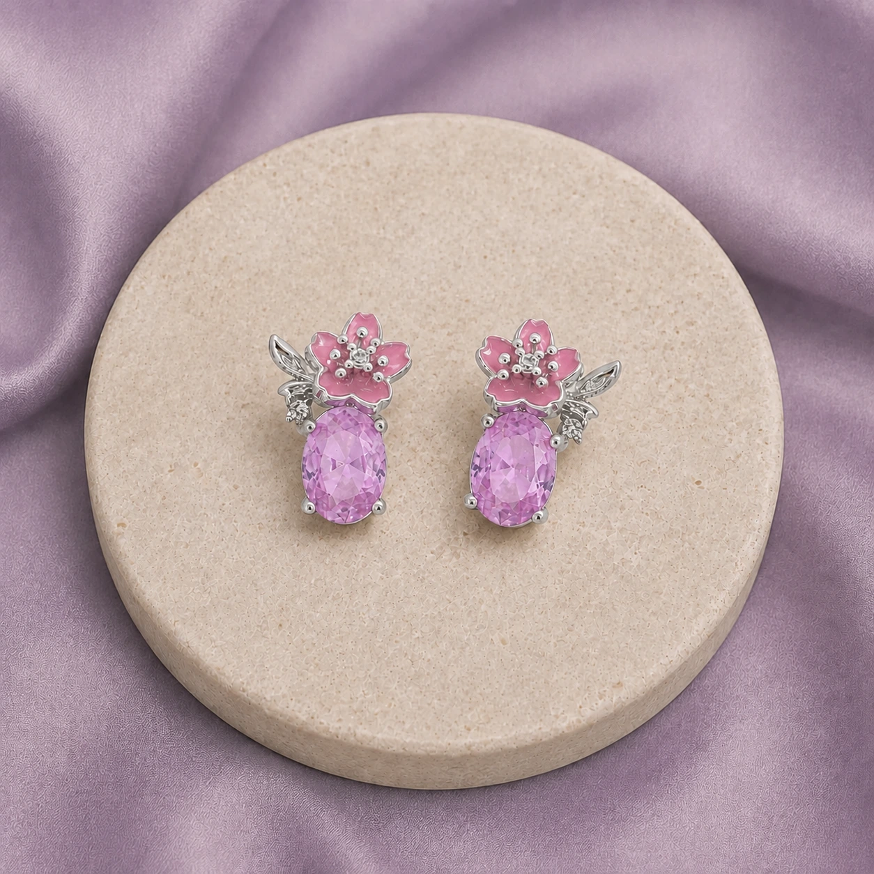 Pink gemstone and floral enamel earrings on ivory stone and muted lilac fabric